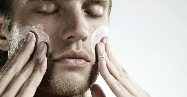 man exfoliating his face